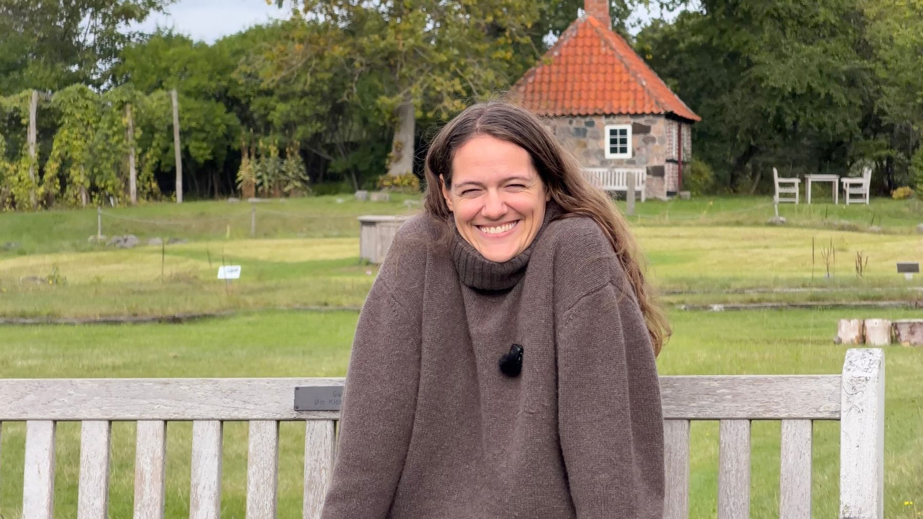 Maiken smiling on a bench in a garden